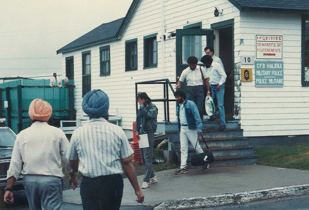 A group of men are seen leaving a small building.