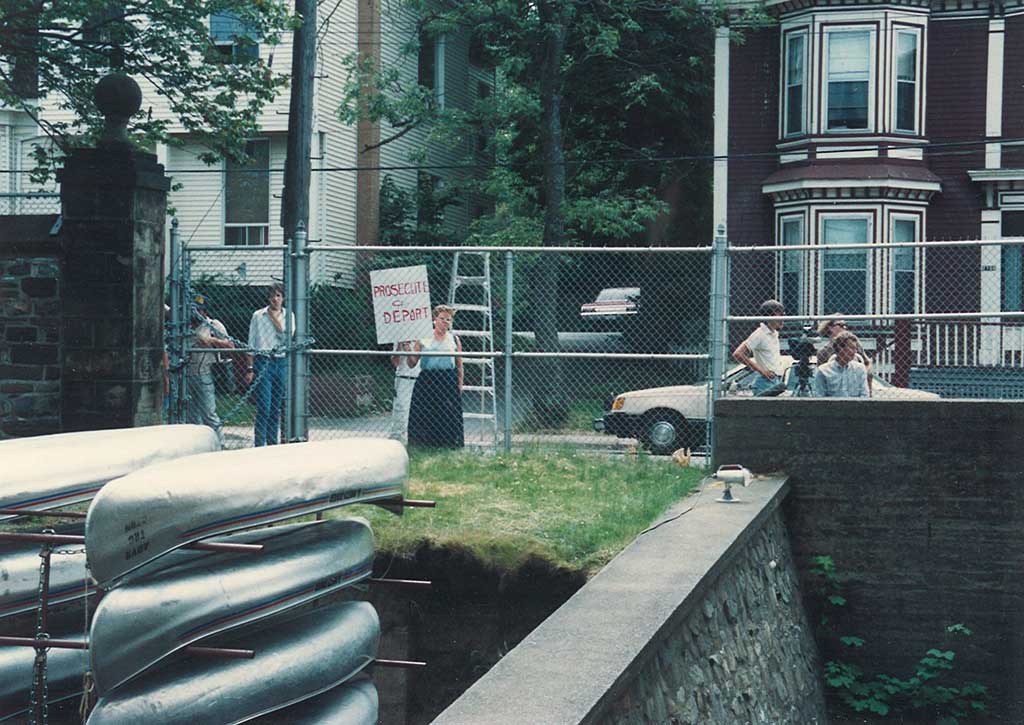 A small group of people are standing on the outside of a fenced in area.