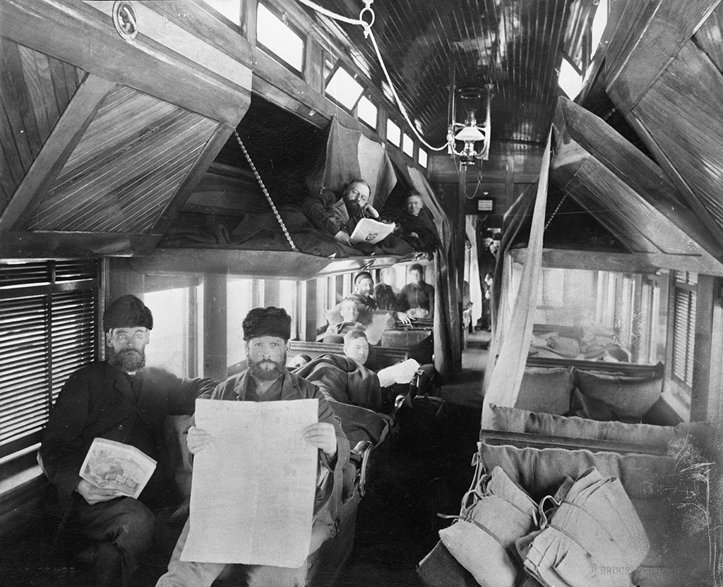 Interior of an old steamer car, showing men in various states of repose.