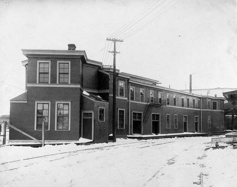 Snow-covered streets and sidewalks in front of a two-storey building.