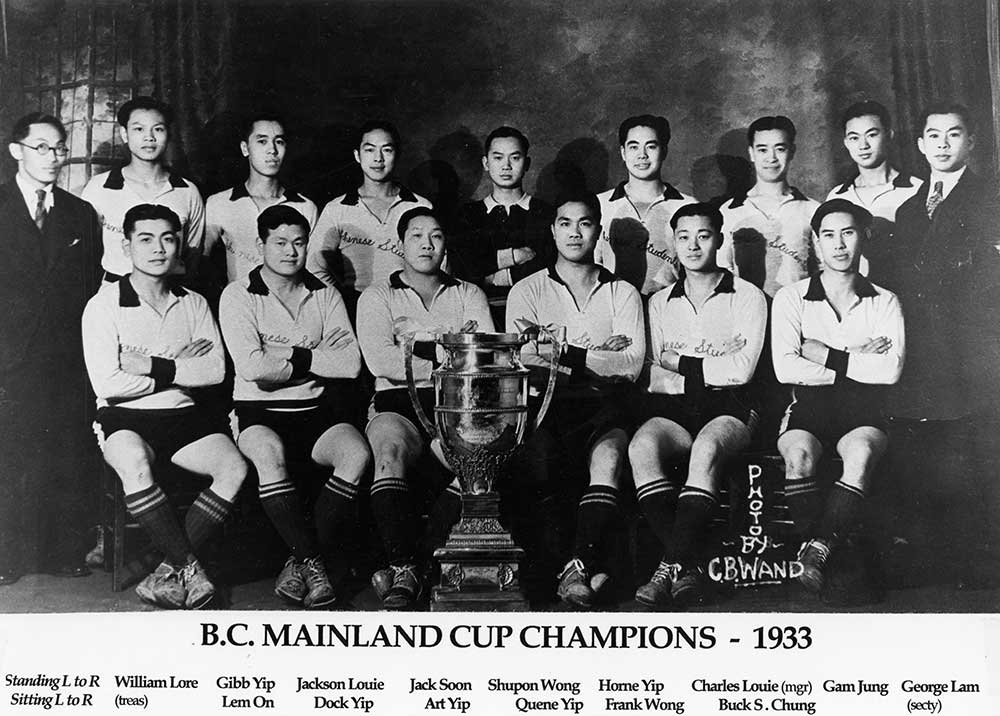 Fifteen young Chinese Canadian men arranged in two rows behind a trophy, most wear light jerseys saying Chinese Students.