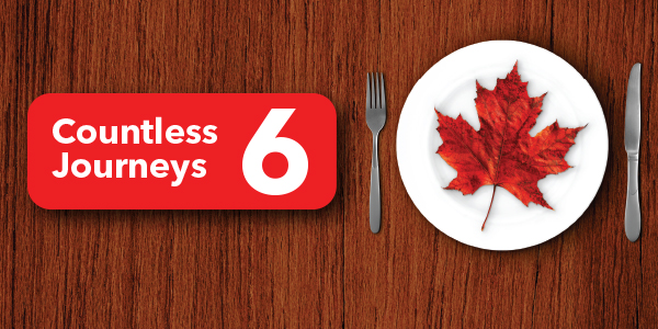 A dinner plate on a wooden surface with a maple leaf on it, a red banner that says Countless Journeys 6.