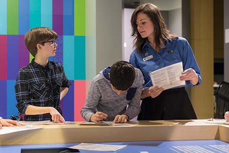 An interpreter watches as two young boys try to complete the Canadian Citizenship test.