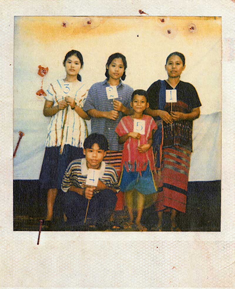 A woman and four children all hold up sticks that have numbered papers glued to them.