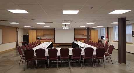 A room with three tables arranged to for a U and a projector screen on the wall.