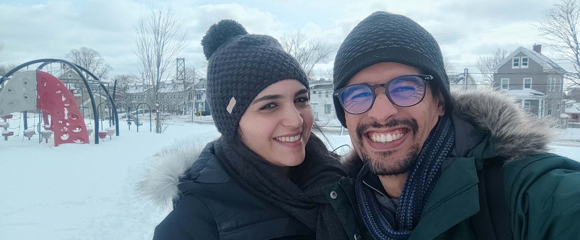 A couple smiles for the camera, outside in the snow.