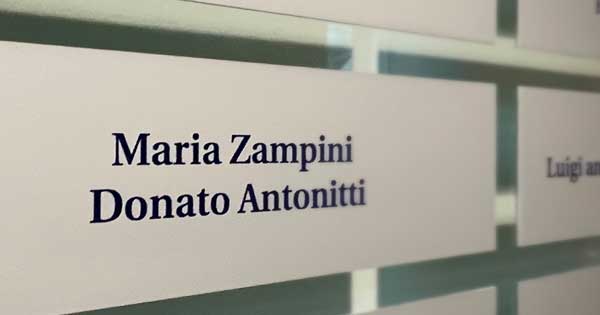A close up of a plaque, amongst a wall of plaques, bearing the names Maria Zampini and Donato Antonitti.