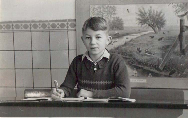 Black and white photo of a boy at a school desk.