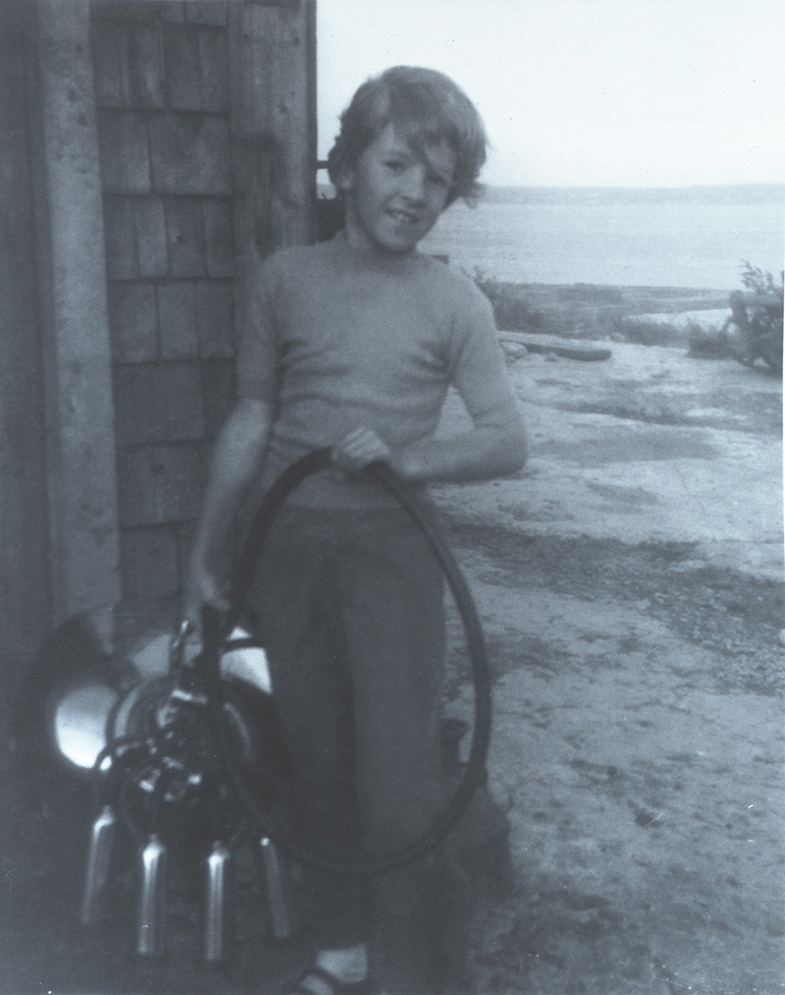 Black and white photo of a smiling girl holding a hose.