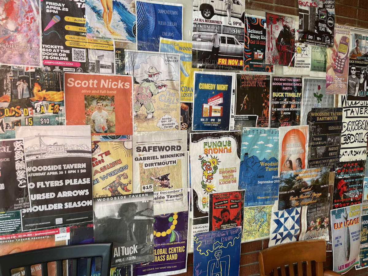 Posters of music shows cover an interior brick wall.