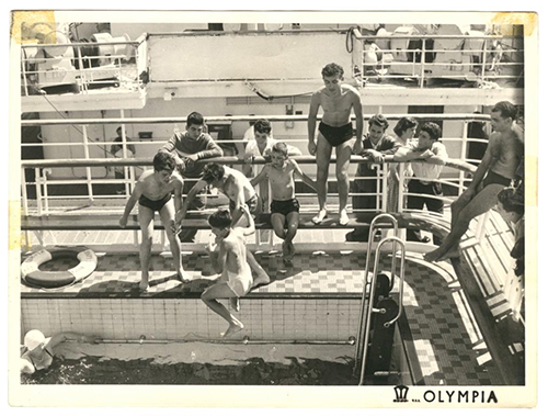 Several young boys jump into a pool aboard ship.