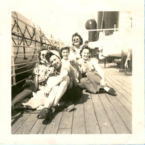 Five young women sit on the deck of a ship.