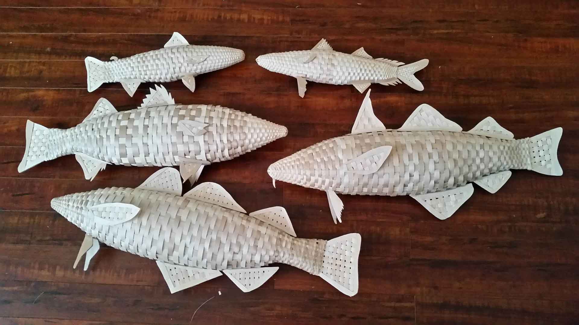 Several species of fish, woven from wood strips.