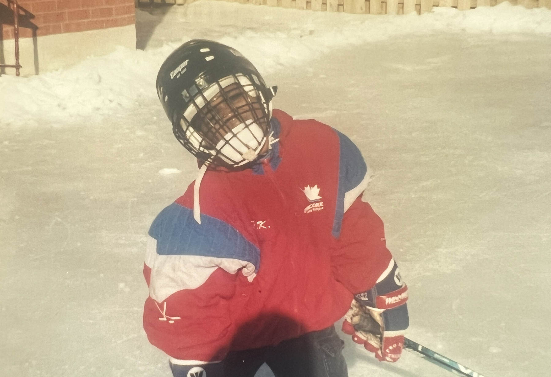 A Black boy, about ten years old, in hockey gear.
