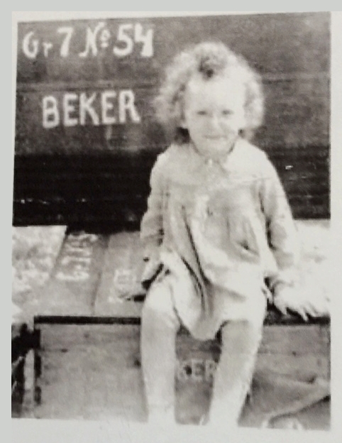 A girl, about 5, sits on a trunk.