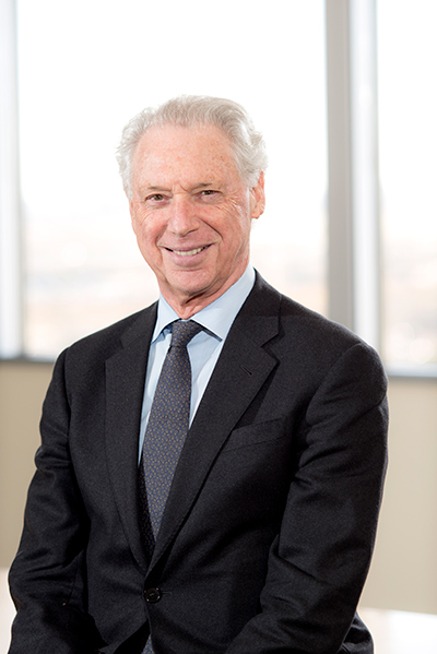 A portrait of a smiling white man wearing a black suit.