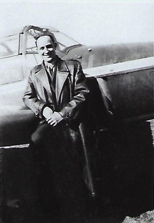 Black and white photograph of a young man leaning against the cabin of a small plane.
