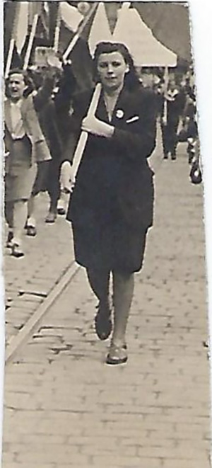 A young lady is holding a flag and walking on a path.