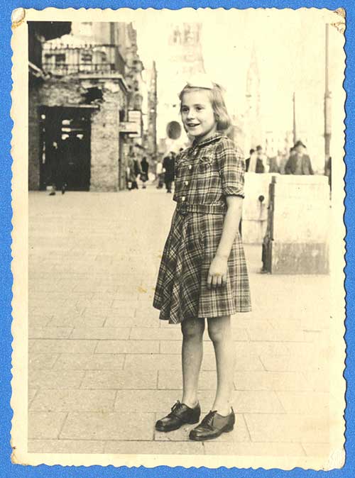 A young girl wearing a dress stands for a photo.