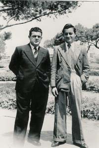 Fred and father in suits standing in garden area.
