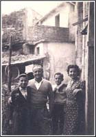 Man and woman with two small boys, standing in front of building.