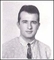 Head and shoulders portrait of young man in sweater vest and tie.