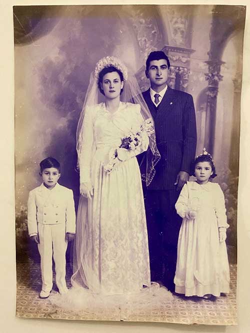 Archival portrait of bride and groom on their wedding day, two small children in white stand with them.