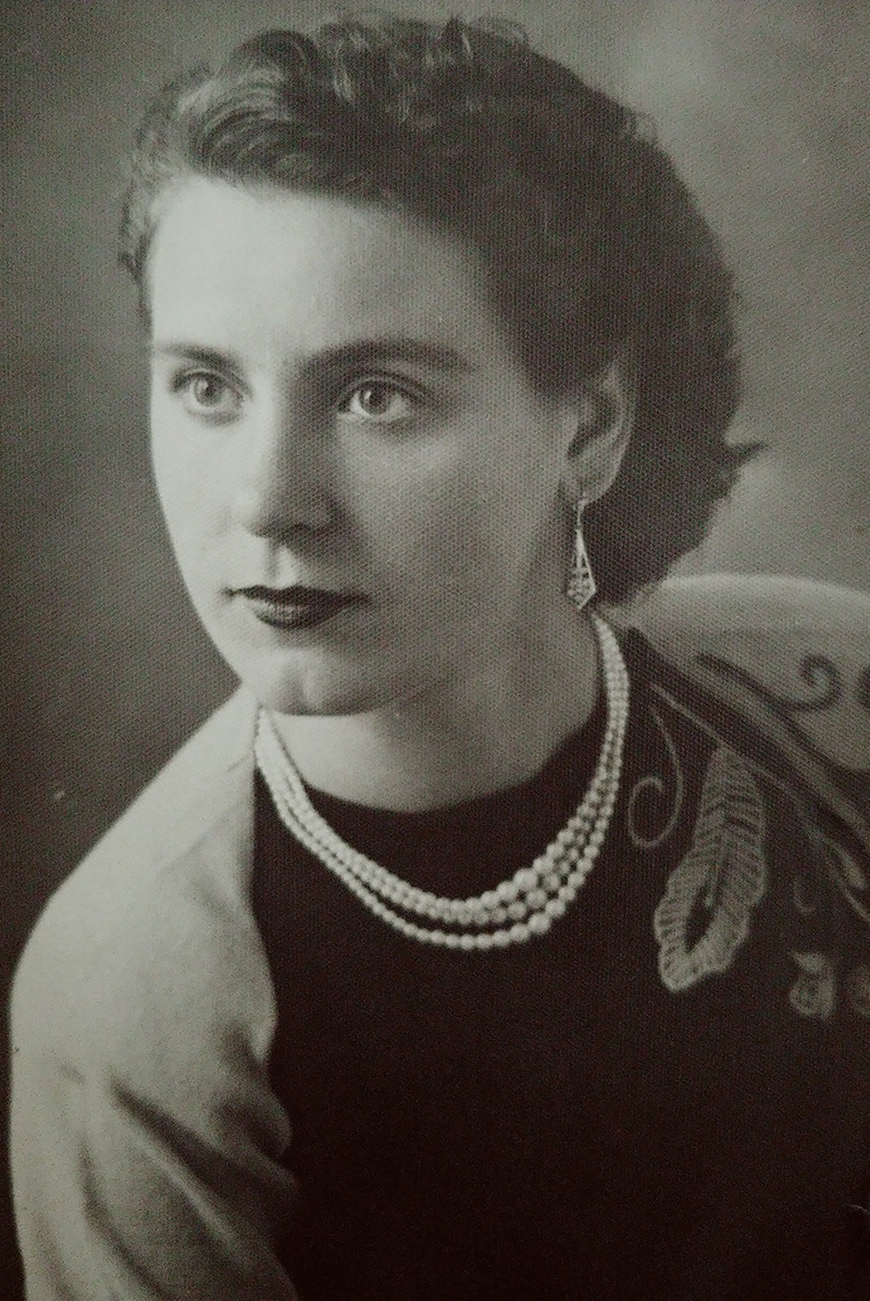 Professional portrait of a young woman with black hair and wearing a pearl necklace.