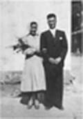 Old photo showing bride and groom on wedding day, bride holding flowers.