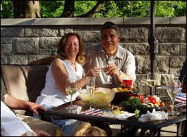 Middle-aged couple seated on outdoor table, toasting the occasion.
