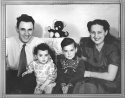 Man and woman with two children seated between them, and teddy bear behind.