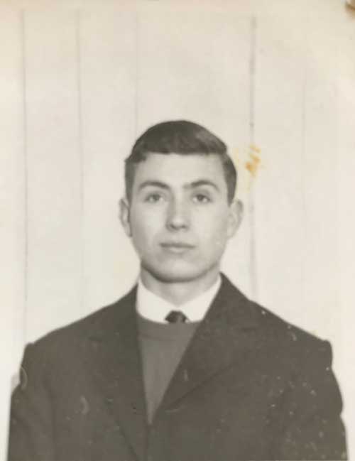Old cracked photograph of a young man in suit and tie.