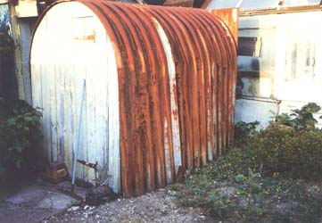Old rusted bomb shelter in the back garden of a house.