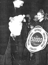 Ausma accepting a doll and sign saying she is the 50 000th refugee.