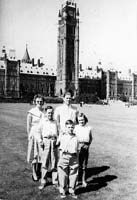 Man, woman and children standing in front of large government building.