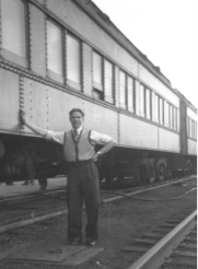 Bernardus in vest and shirt, with one hand against train.