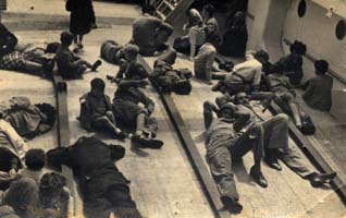 Young people sprawled out on the deck of the ship.
