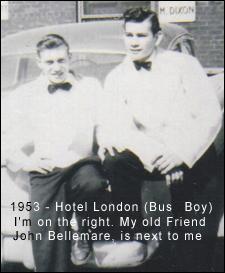 Two young men in bus boy uniforms, leaning against a car.
