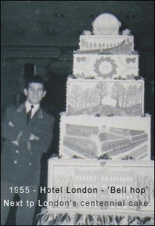 Young Bruno as a bell hop, standing next to celebratory cake as tall as him.