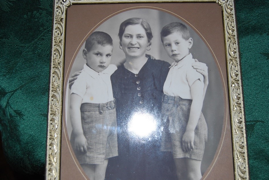 A picture frame with a black and white photo of a woman posing with two children.