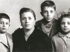 Family portrait with woman surrounded by two small boys and one girl.