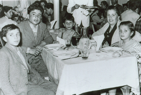 A woman seated at a table with four boys of varying ages.