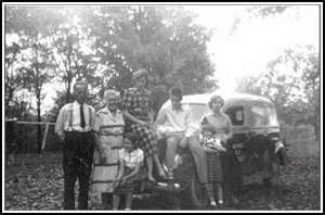 Old photograph showing the family in front of an old car model. 