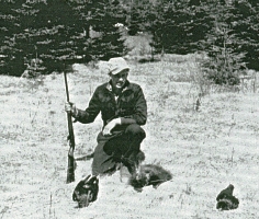 Young Cornelius down on one knee, holding gun with 2 dead crows and one rabbit on ground.