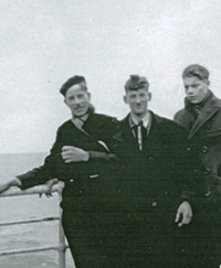 Cornelius and two young men leaning against railing aboard ship.