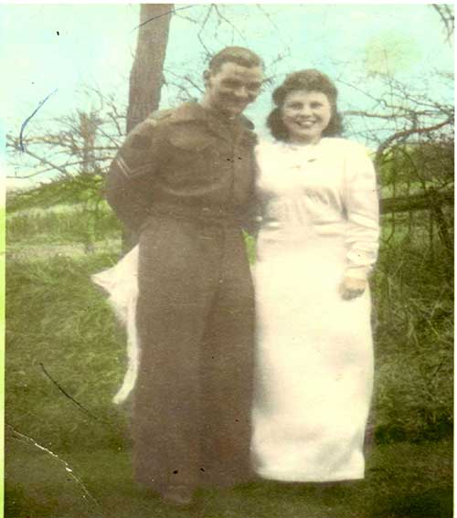 A young man and woman stand in front of a tree.