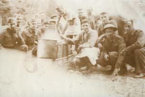 Old photo showing several young men squatting around someone standing.