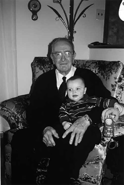 A man sits in an armchair with a baby on his lap.