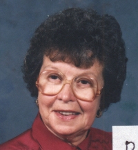 Head portrait of older Daphne, wearing glasses and a burgundy top.