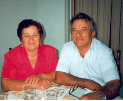 Coloured photo of older Pompilio and Rosa, sitting at table.